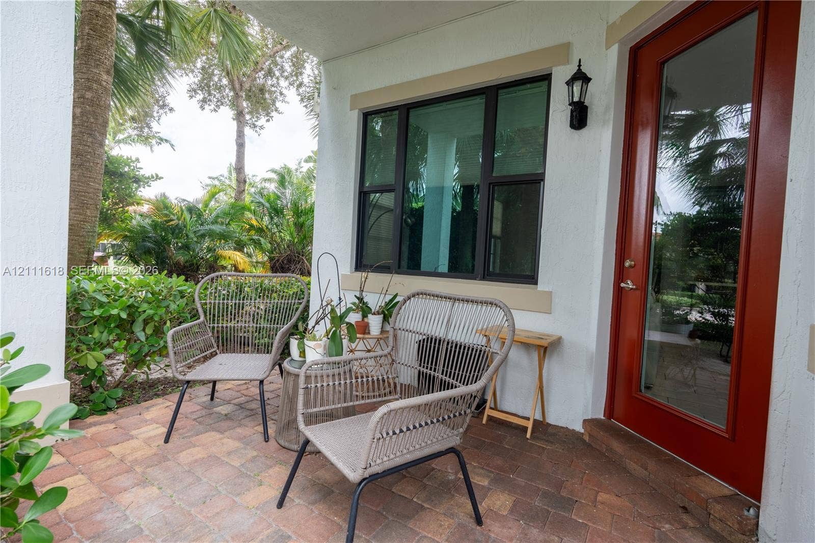 1423 SW 115th Avenue, #NA, Pembroke Pines, Pembroke Pines, FL 33025 Covered entryway featuring a paver patio, a red-finished glass-paneled door, large multi-pane windows, and a wall-mounted exterior sconce