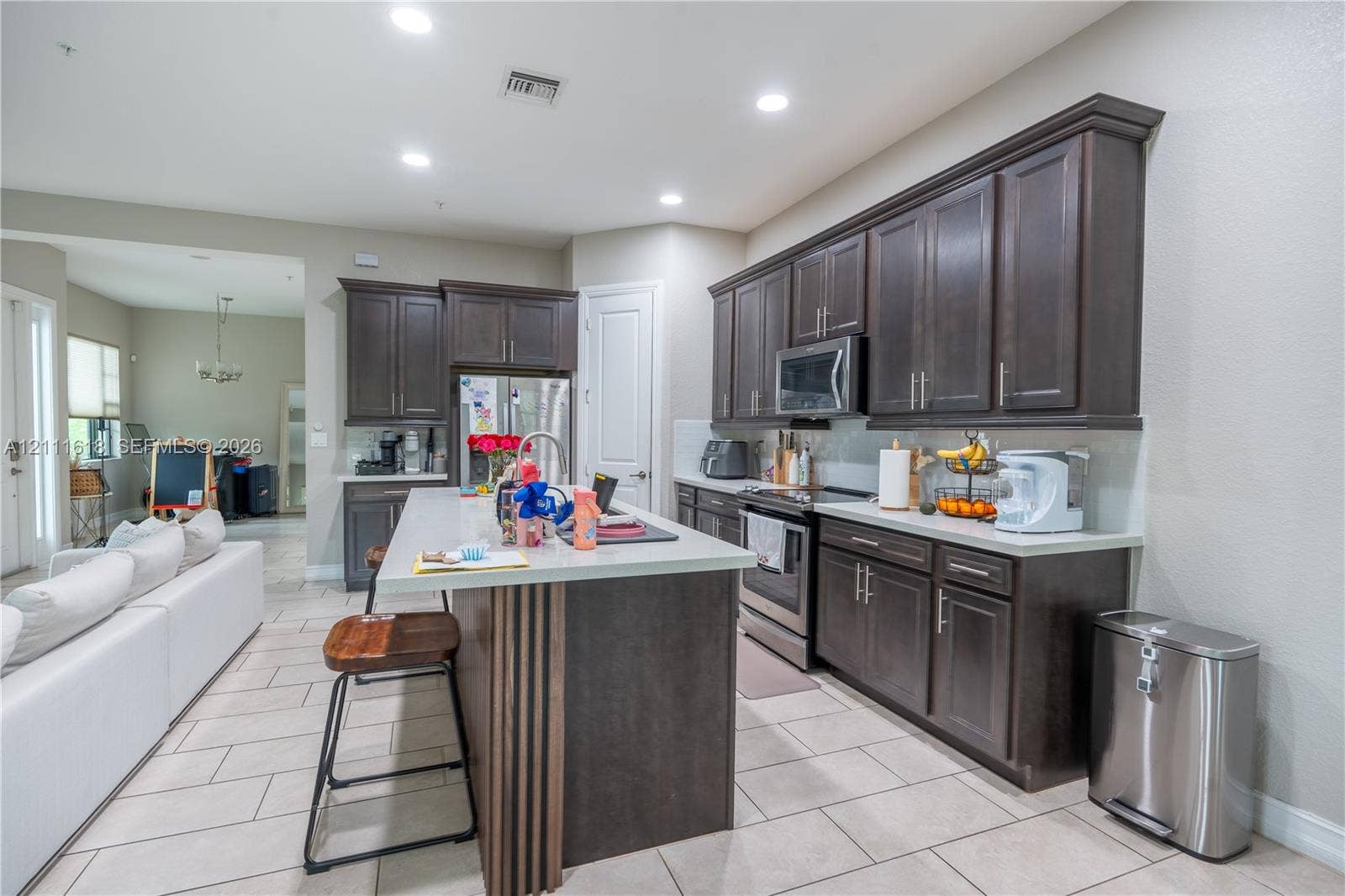1423 SW 115th Avenue, #NA, Pembroke Pines, Pembroke Pines, FL 33025 Kitchen featuring dark wood cabinetry, a central island with a stone-finish countertop, recessed lighting, and tile flooring