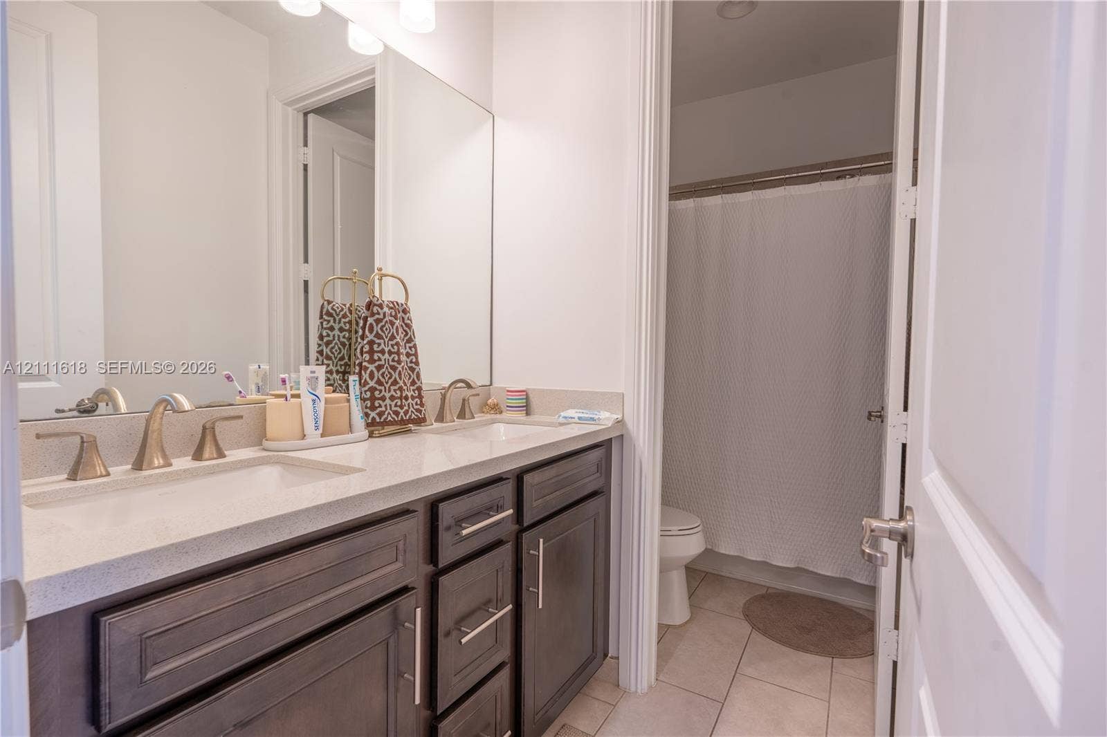 1423 SW 115th Avenue, #NA, Pembroke Pines, Pembroke Pines, FL 33025 Bathroom featuring a dual-sink vanity with light-toned solid surface countertops, dark-finish cabinetry, metallic hardware, and a tub-shower combination with tile flooring