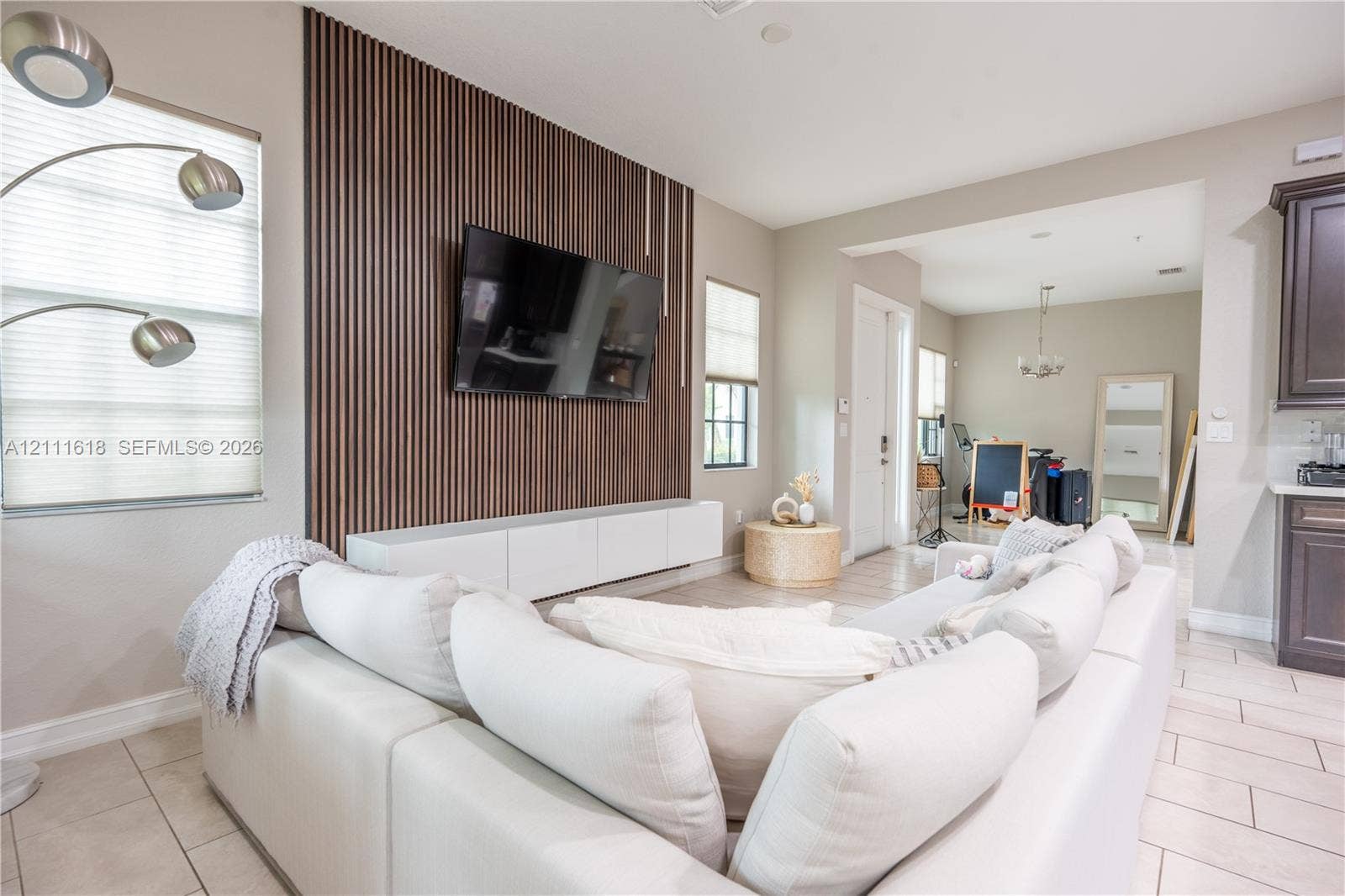 1423 SW 115th Avenue, #NA, Pembroke Pines, Pembroke Pines, FL 33025 Vertical wood-slat accent wall featuring a white floating media console and light-toned tile flooring
