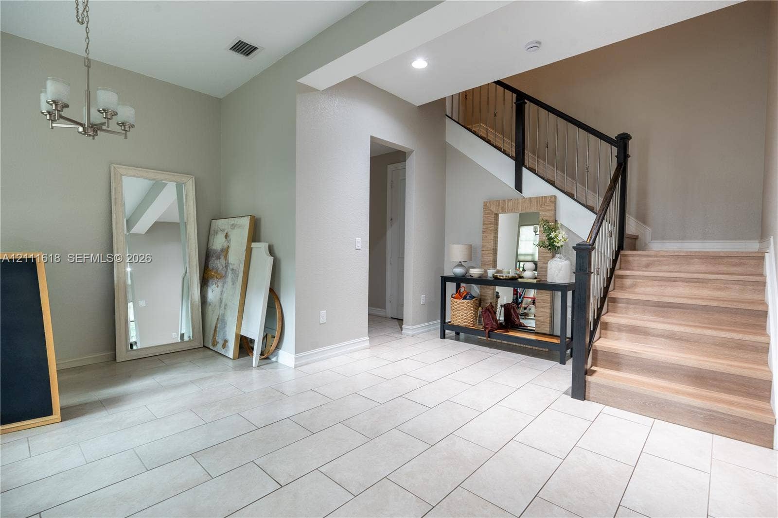 1423 SW 115th Avenue, #NA, Pembroke Pines, Pembroke Pines, FL 33025 Foyer featuring large-format ceramic tile flooring, a staircase with wood-finish treads, a black metal balustrade, recessed lighting, and a multi-arm pendant fixture