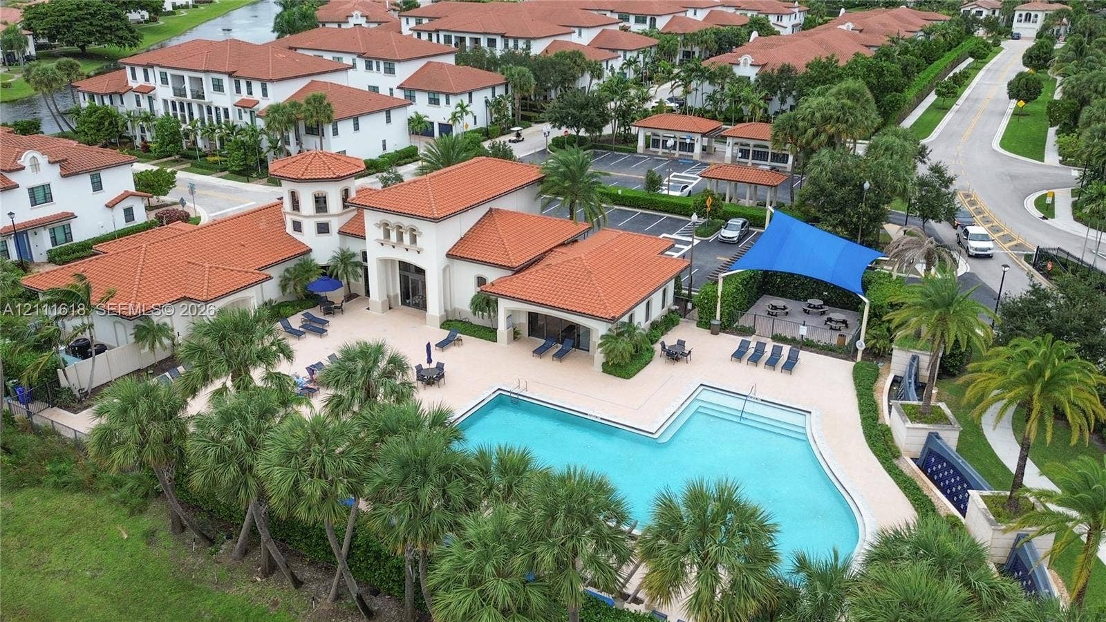 1423 SW 115th Avenue, #NA, Pembroke Pines, Pembroke Pines, FL 33025 Community center featuring a swimming pool, clay-tile roof architecture, expansive pool deck, shaded canopy area, and mature palm landscaping