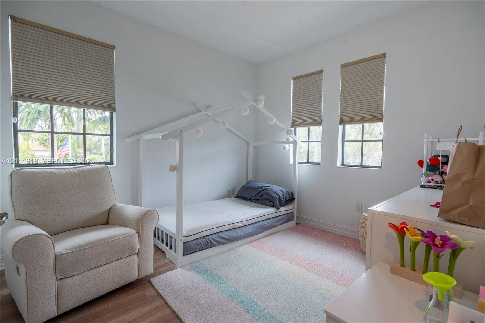 1423 SW 115th Avenue, #NA, Pembroke Pines, Pembroke Pines, FL 33025 Bright bedroom featuring wood-finish flooring, three windows with grid-pattern muntins, and neutral cellular shades