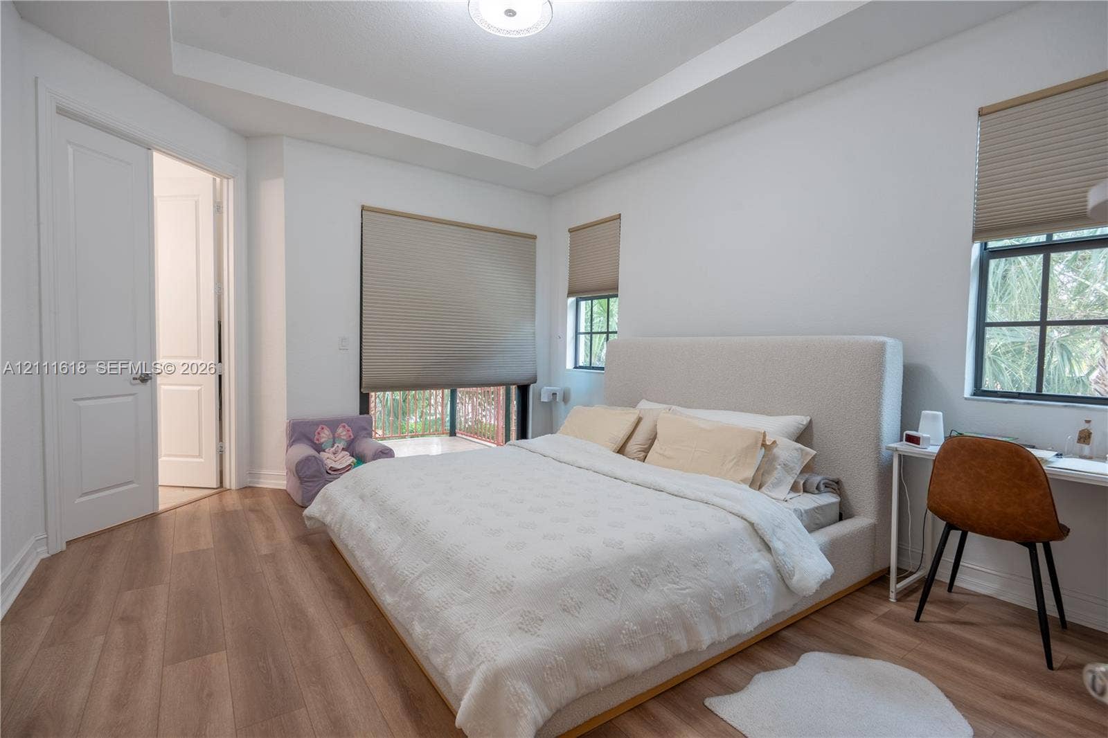 1423 SW 115th Avenue, #NA, Pembroke Pines, Pembroke Pines, FL 33025 Bedroom featuring a tray ceiling, wood-finish flooring, multi-pane windows with integrated shades, and a solid-core interior door