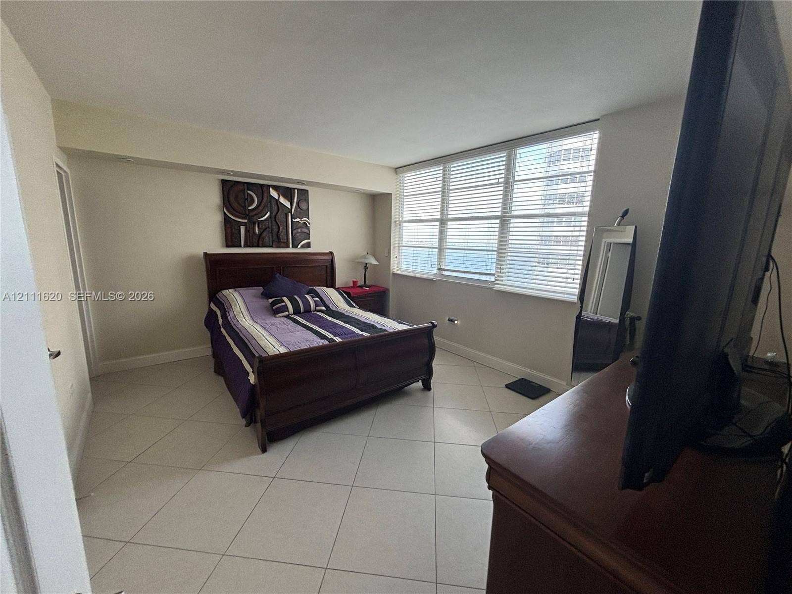 Light-filled room featuring neutral tile flooring, expansive multi-pane windows, and horizontal blinds