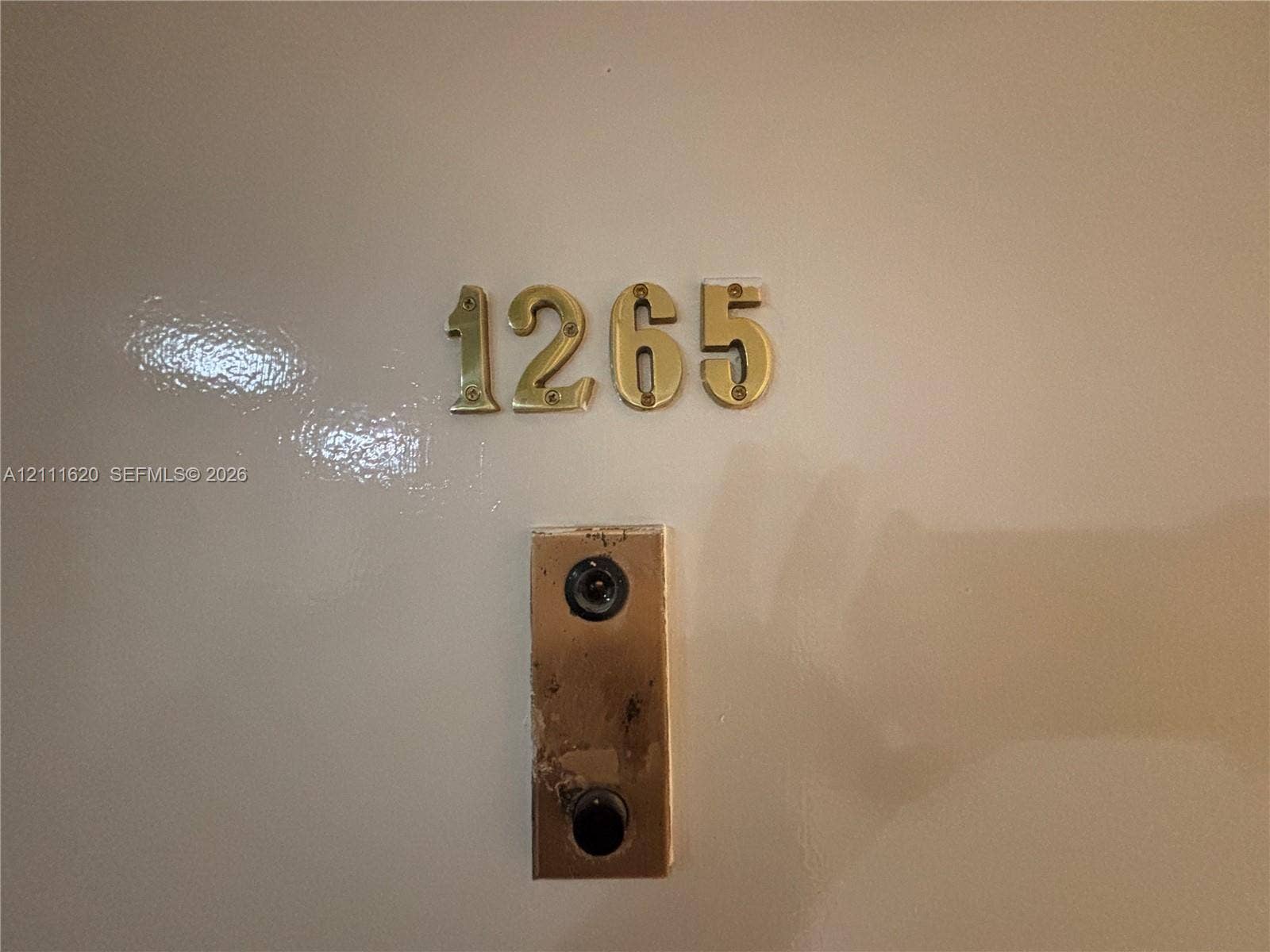Brass-finish metal door address numbers and a matching vertical door chime plate