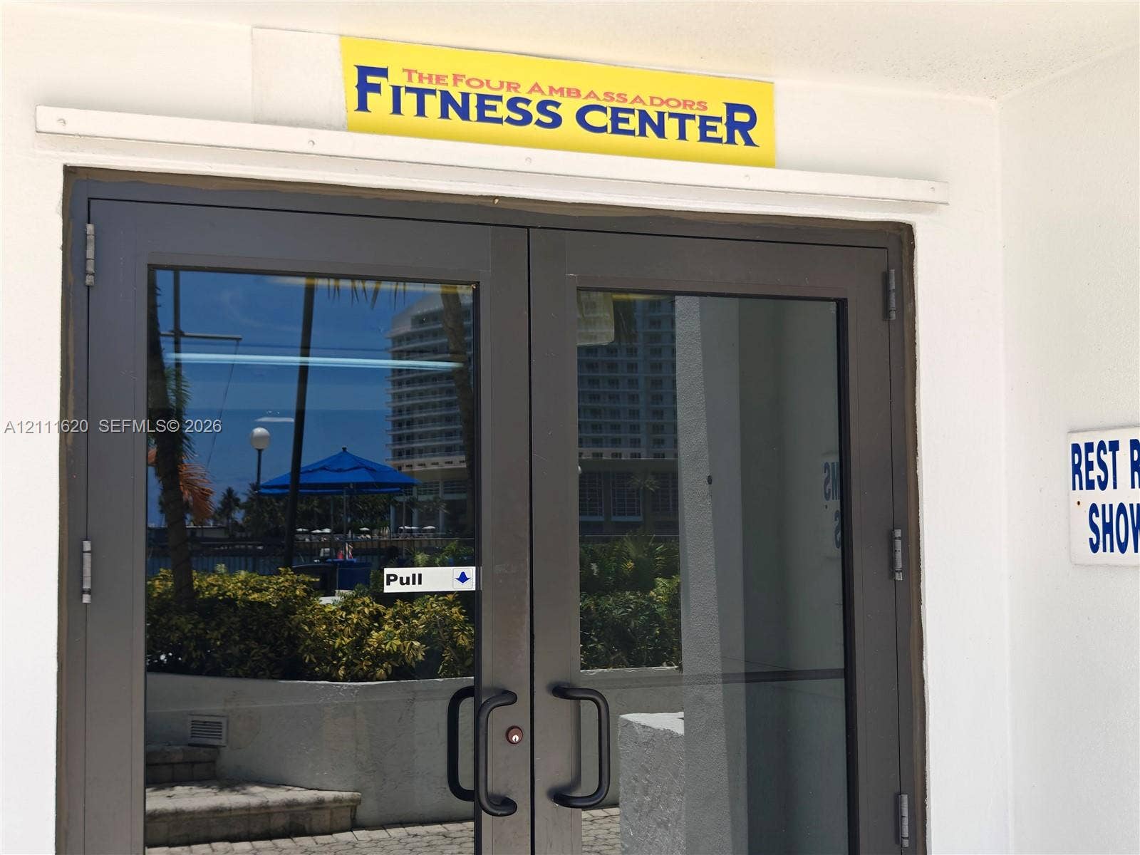 Fitness center entrance featuring bronze-finished double glass doors and directional signage