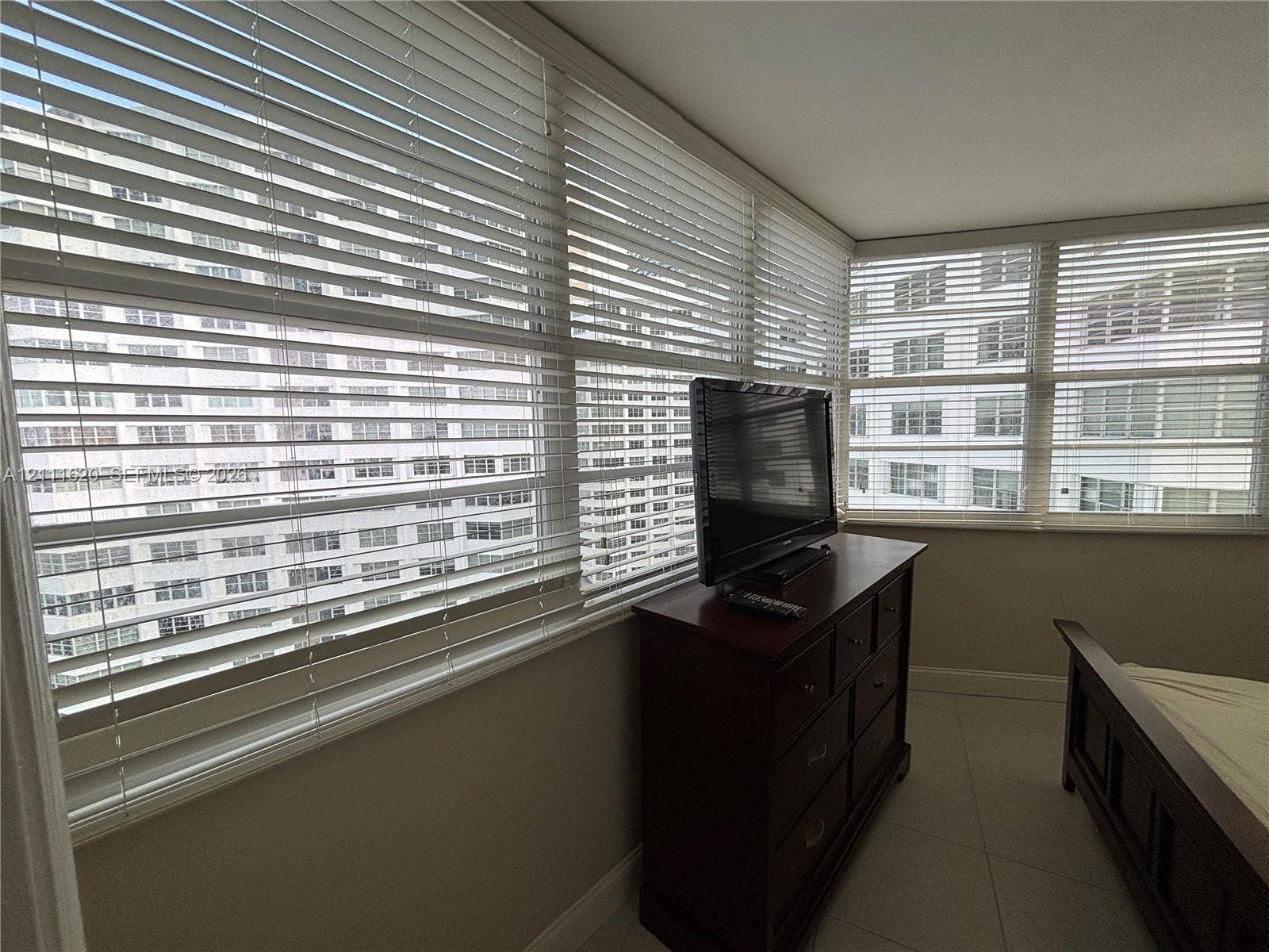 Expansive multi-pane windows featuring horizontal blinds and tile-finish flooring