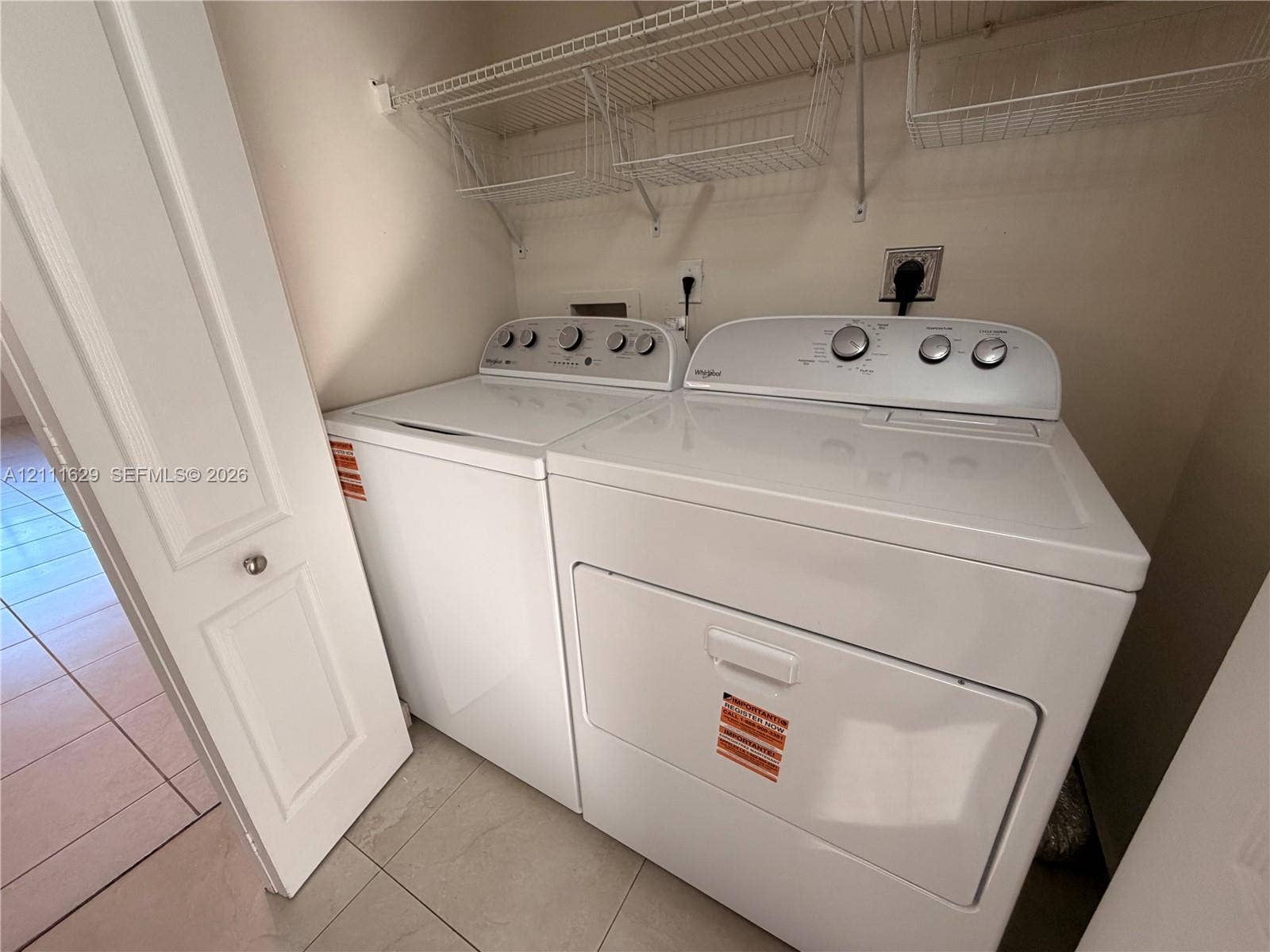 Laundry closet featuring tile flooring, bi-fold door, and overhead wire shelving