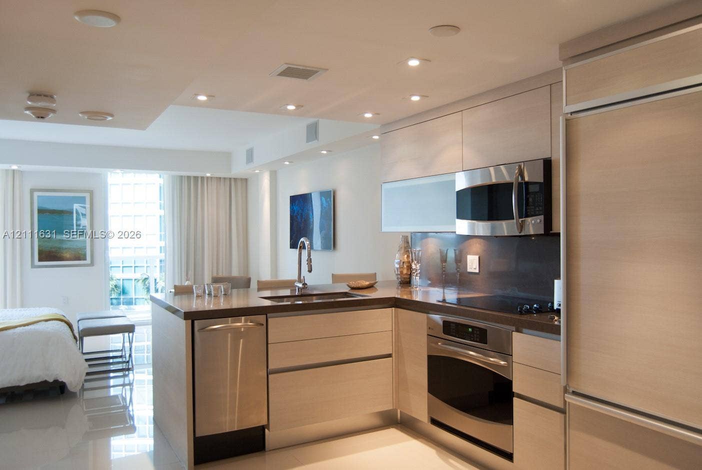 Kitchen featuring light-finish cabinetry, stainless steel appliances, integrated dishwasher, solid-surface countertops, and recessed ceiling lighting