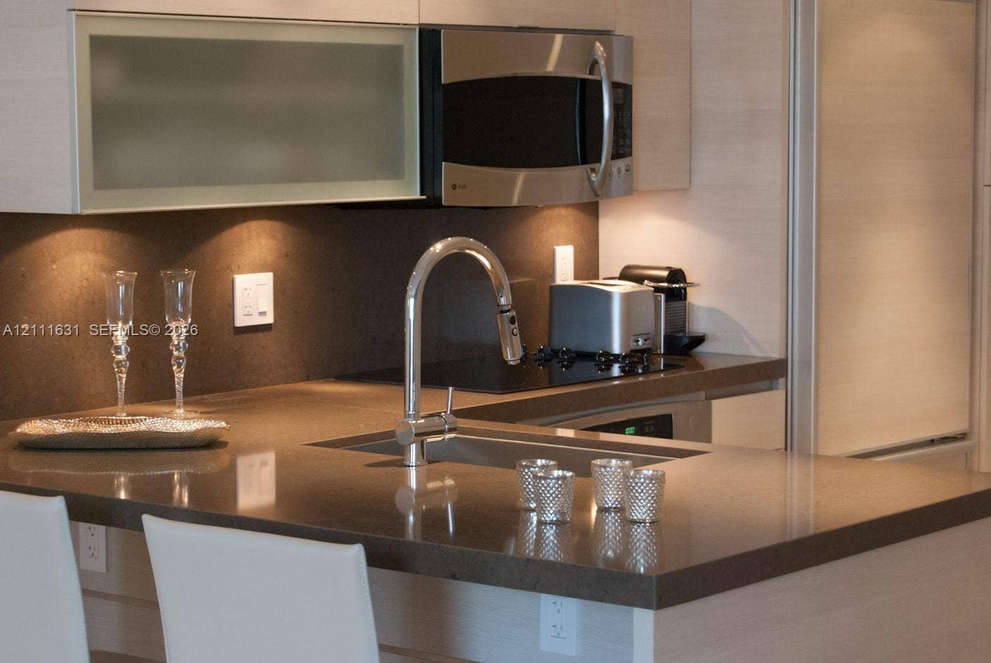 Kitchen featuring wood-finish cabinetry, quartz countertops, a stainless steel undermount sink with a gooseneck faucet, and an integrated stainless steel microwave