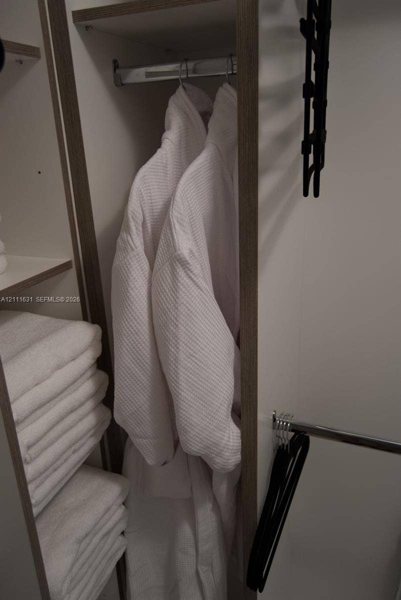Built-in storage closet featuring wood-finish shelving and chrome hanging rods