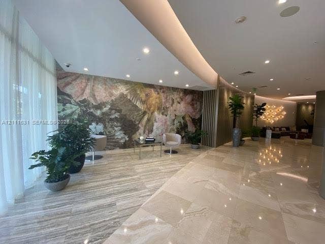 Polished stone flooring, floor-to-ceiling sheer window treatments, decorative feature wall with floral mural, and recessed lighting
