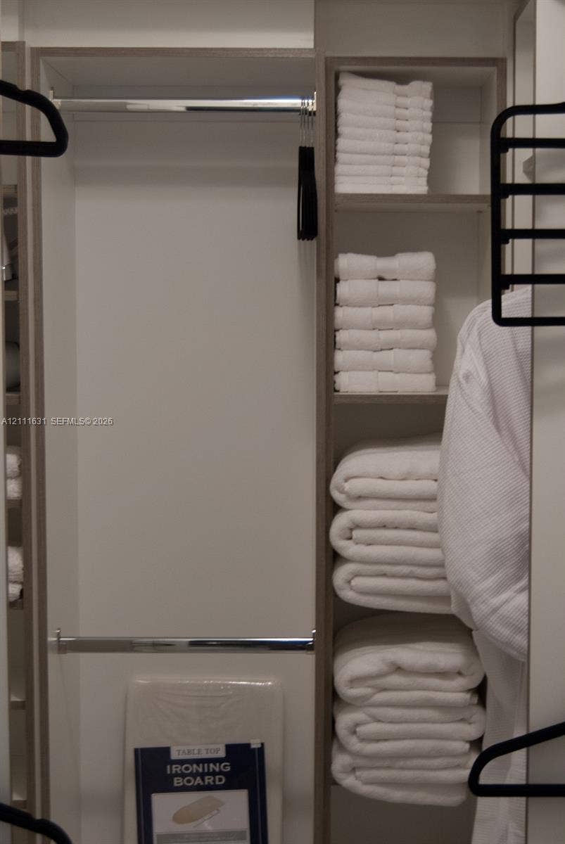 Custom reach-in closet featuring built-in vertical shelving, dual chrome hanging rods, and neutral-toned cabinetry finishes
