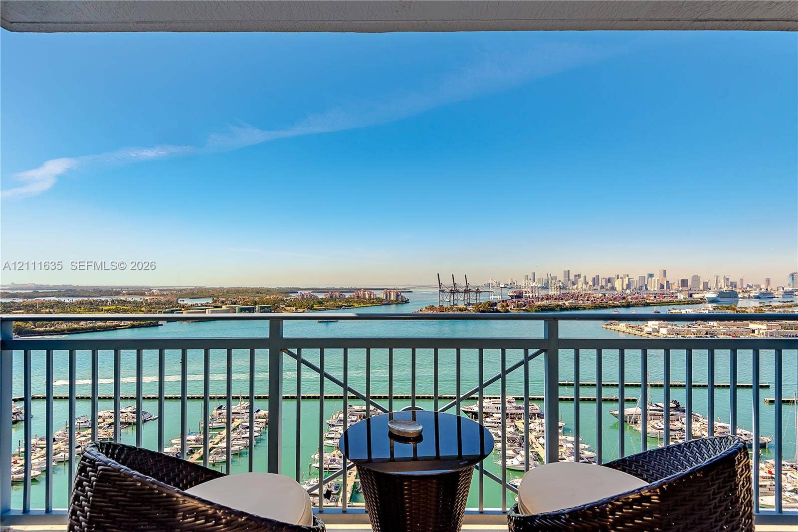 90 Alton Road, #2410, Miami Beach, FL 33139 Covered balcony with metallic railing overlooking a marina and distant urban skyline