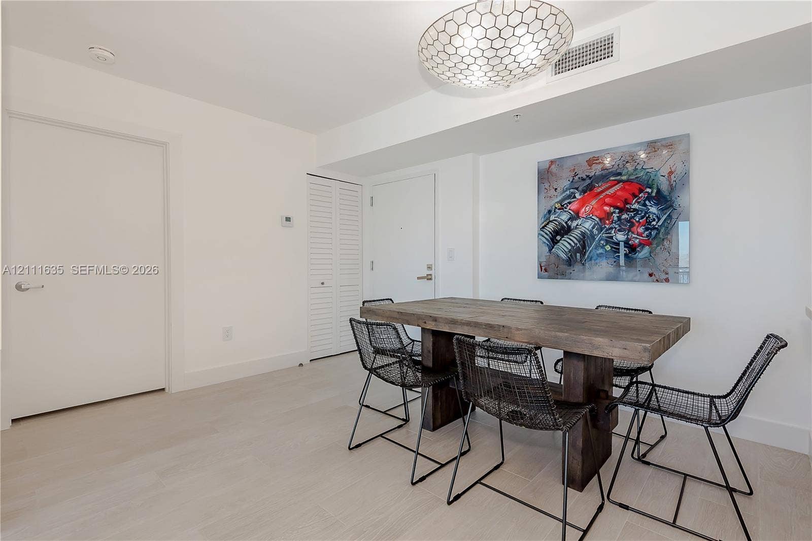 90 Alton Road, #2410, Miami Beach, FL 33139 Neutral-toned interior featuring light-toned wood-finish flooring, a decorative geometric flush-mount light fixture, and floor-to-ceiling white bi-fold closet doors