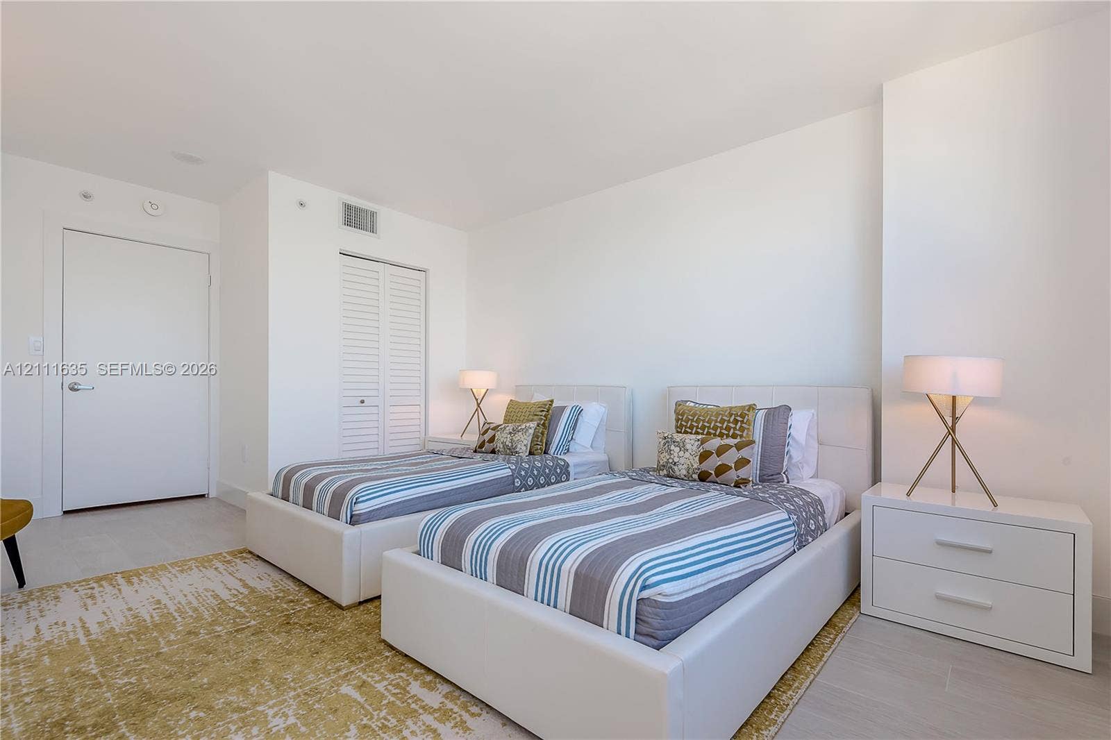 90 Alton Road, #2410, Miami Beach, FL 33139 Neutral-toned interior featuring light wood-finish flooring, white walls, and a closet with louvered doors