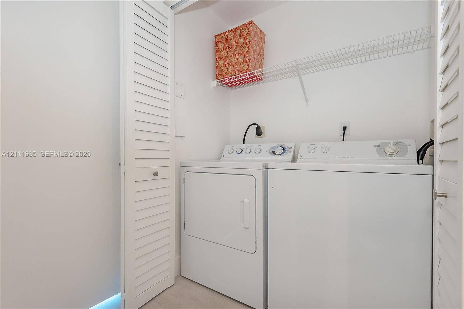 90 Alton Road, #2410, Miami Beach, FL 33139 Laundry closet featuring white louvered doors, wire shelving, and dedicated hookups for a washer and dryer