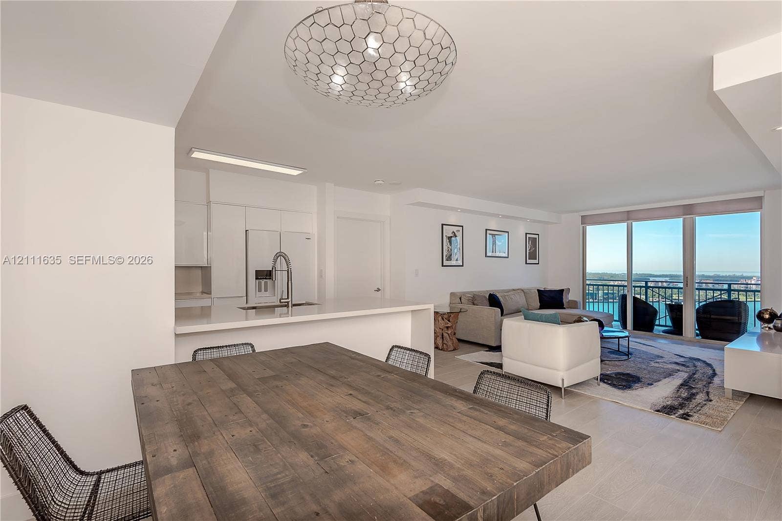 90 Alton Road, #2410, Miami Beach, FL 33139 Open-concept floor plan featuring a kitchen with a white quartz breakfast bar, stainless steel faucet, and recessed lighting, finished with tile flooring and a geometric ceiling pendant