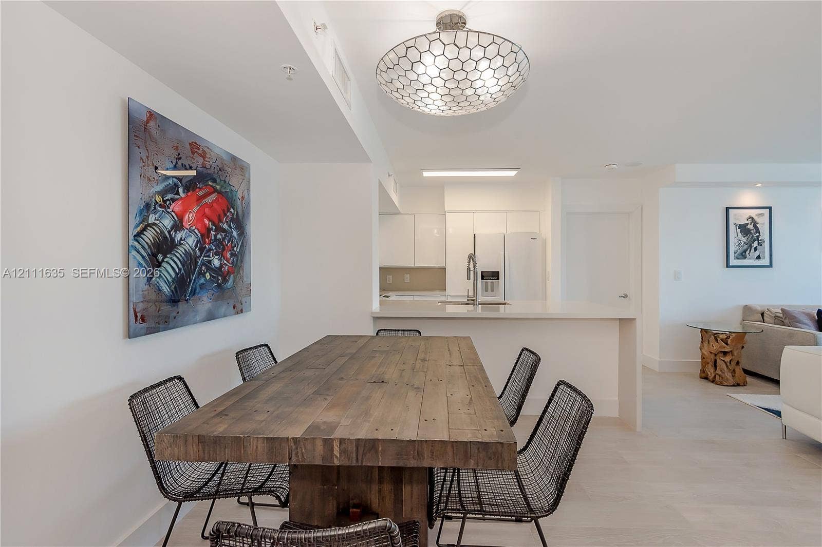 90 Alton Road, #2410, Miami Beach, FL 33139 Open-concept interior featuring light-toned flooring, geometric patterned ceiling fixture, and kitchen peninsula with integrated countertop