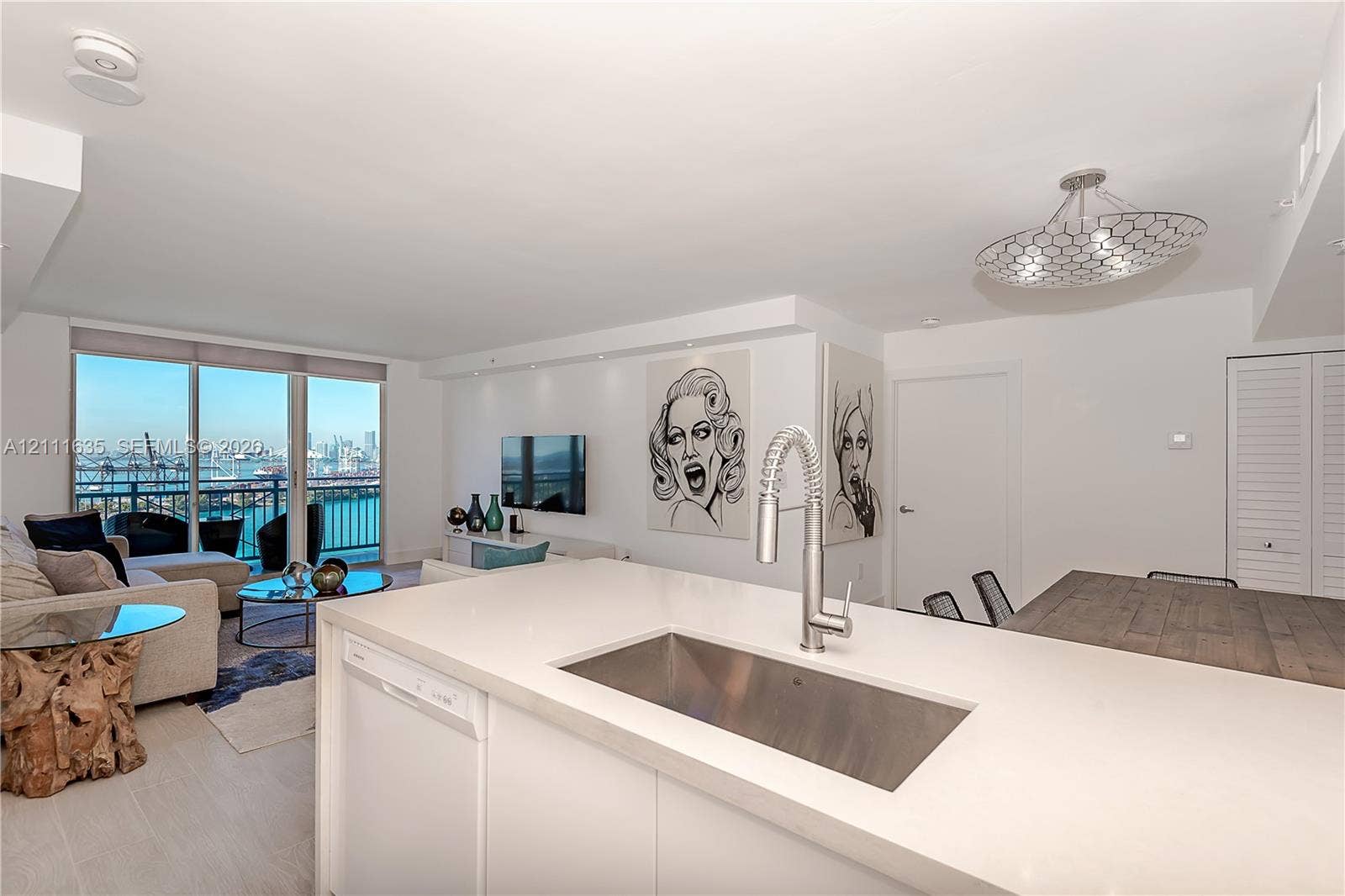 90 Alton Road, #2410, Miami Beach, FL 33139 Kitchen featuring a white countertop with an integrated stainless steel rectangular sink and gooseneck faucet, floor-to-ceiling windows, and a decorative geometric ceiling fixture