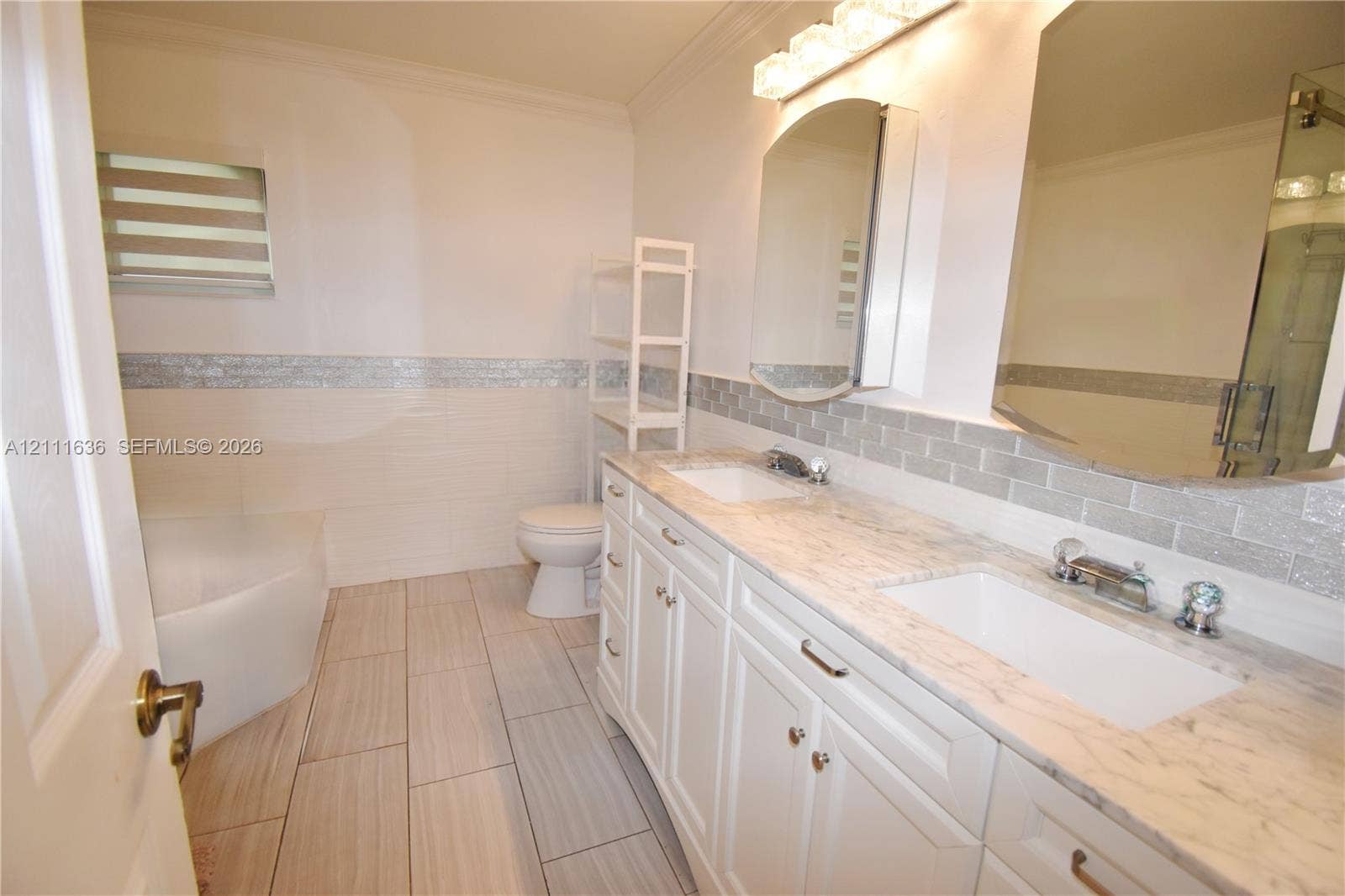 Double vanity featuring stone-finish countertops, undermount sinks, shiplap-style wall tiling with a glass tile accent border, and rectangular floor tiling