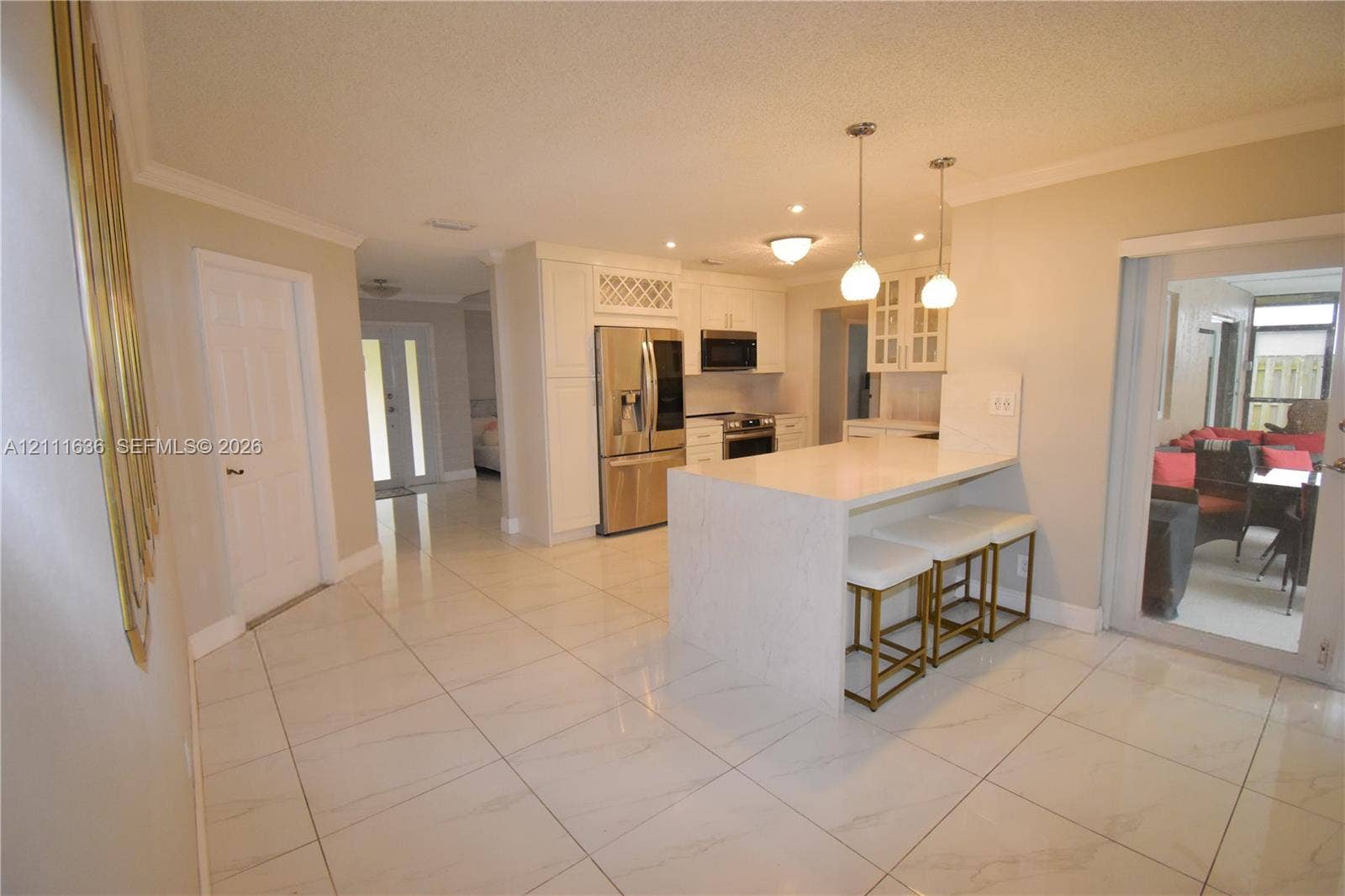 Kitchen featuring white cabinetry, stainless steel appliances, stone-finish countertops, a breakfast bar, and polished tile flooring