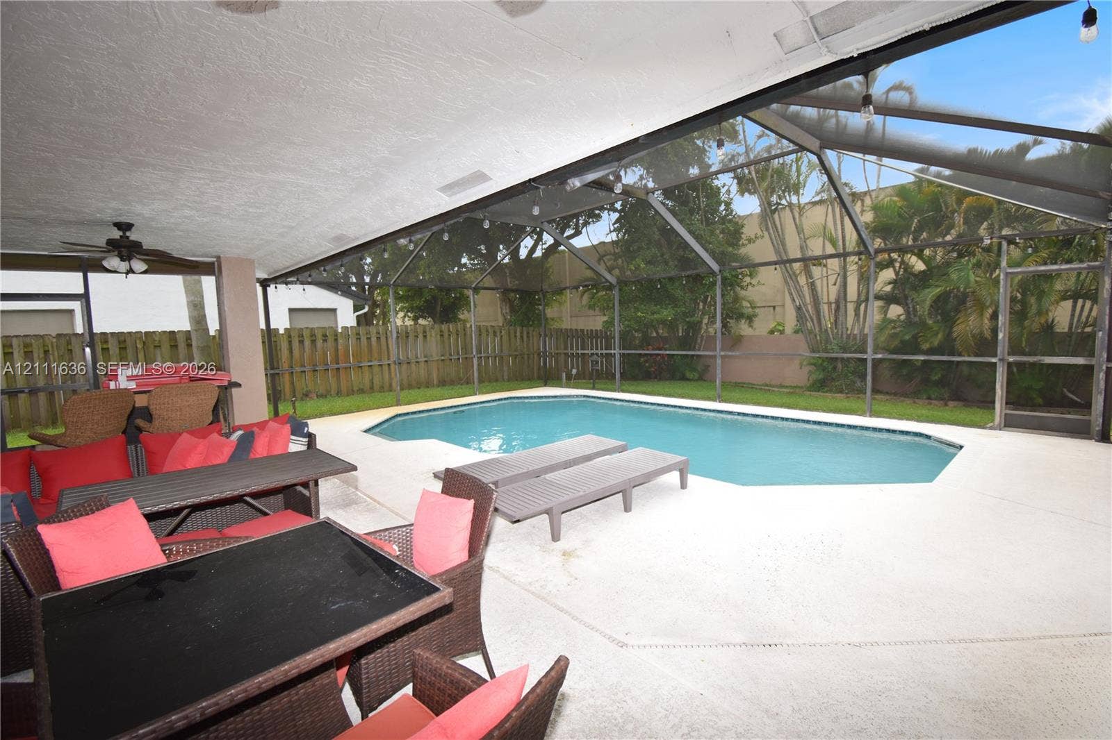 Screen-enclosed patio with a concrete deck, in-ground swimming pool, and wood-style privacy fencing