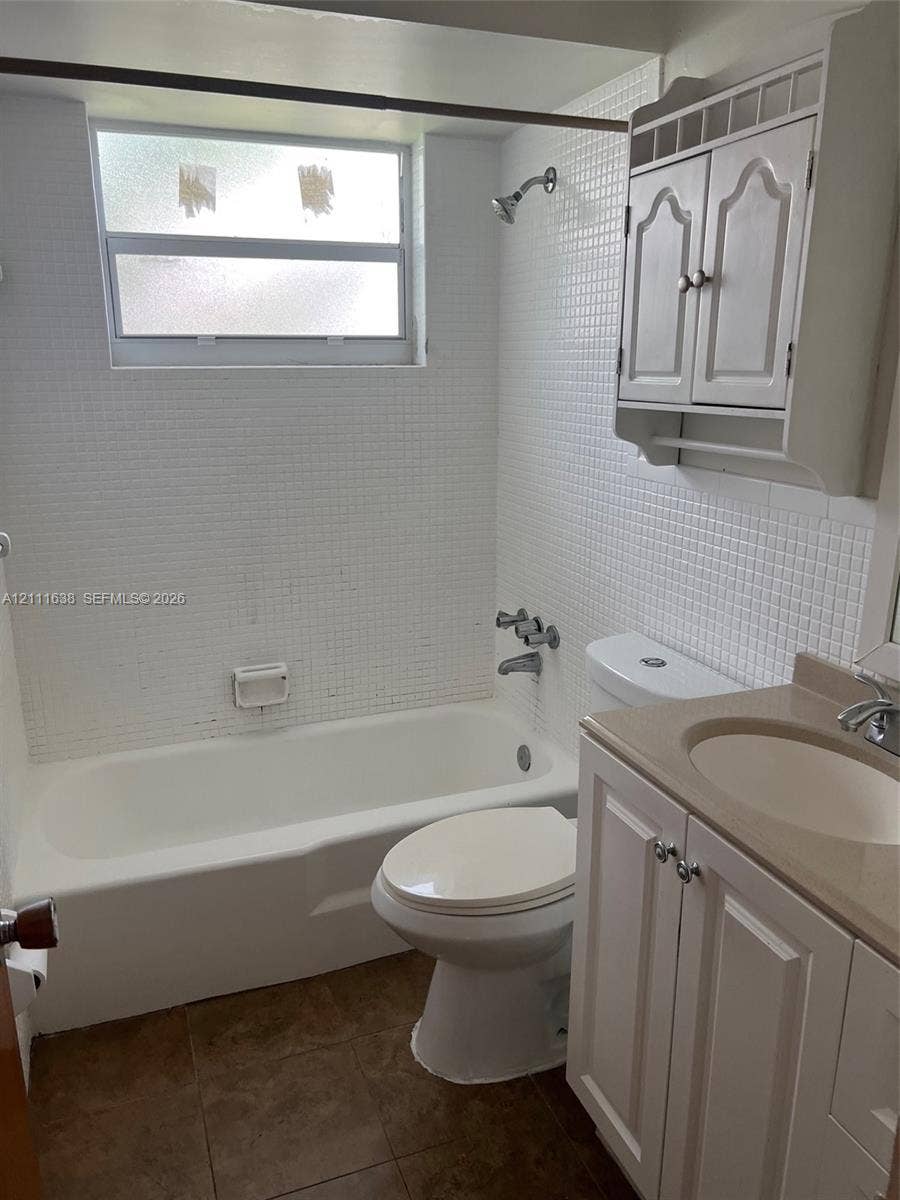 4841 SW 45th Avenue, #2, Hollywood, Hollywood, FL 33314 Bathroom featuring a porcelain tub with white tiled surround, integrated white cabinetry, vanity with countertop basin, and wall-mounted storage unit
