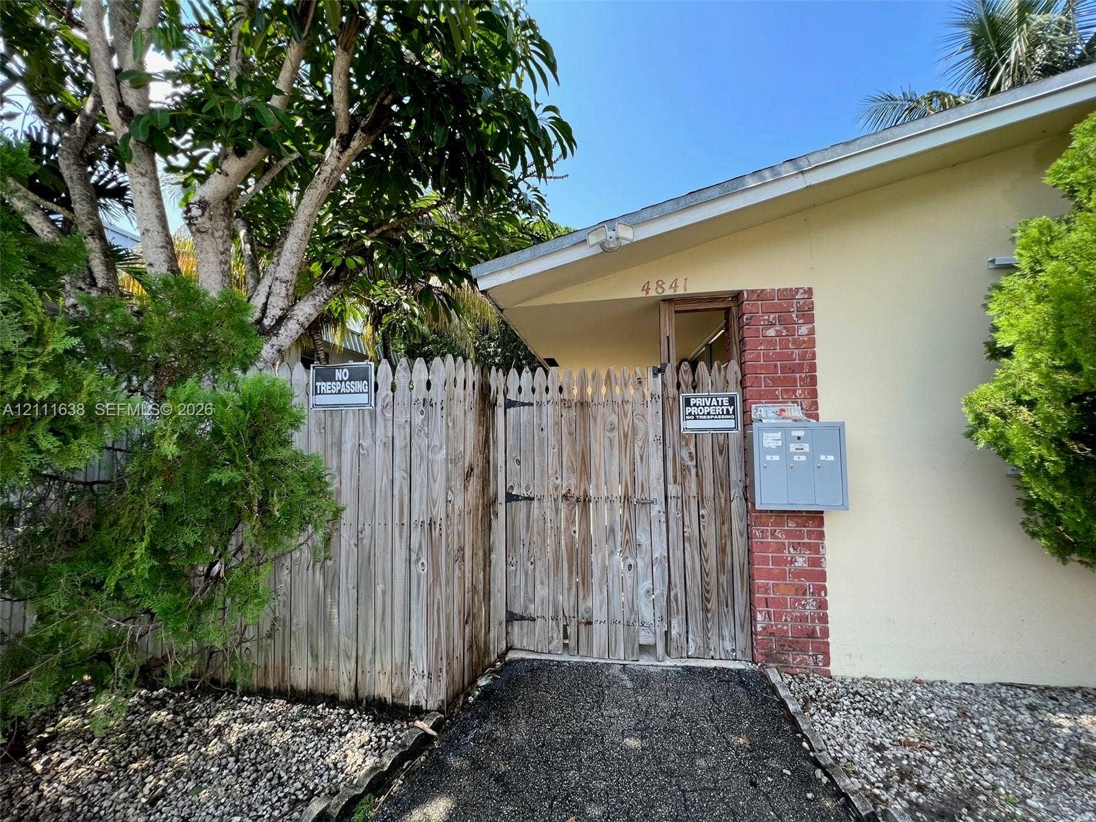 4841 SW 45th Avenue, #2, Hollywood, Hollywood, FL 33314 Exterior facade featuring brick masonry accents, a wooden privacy fence, and integrated mail collection receptacles