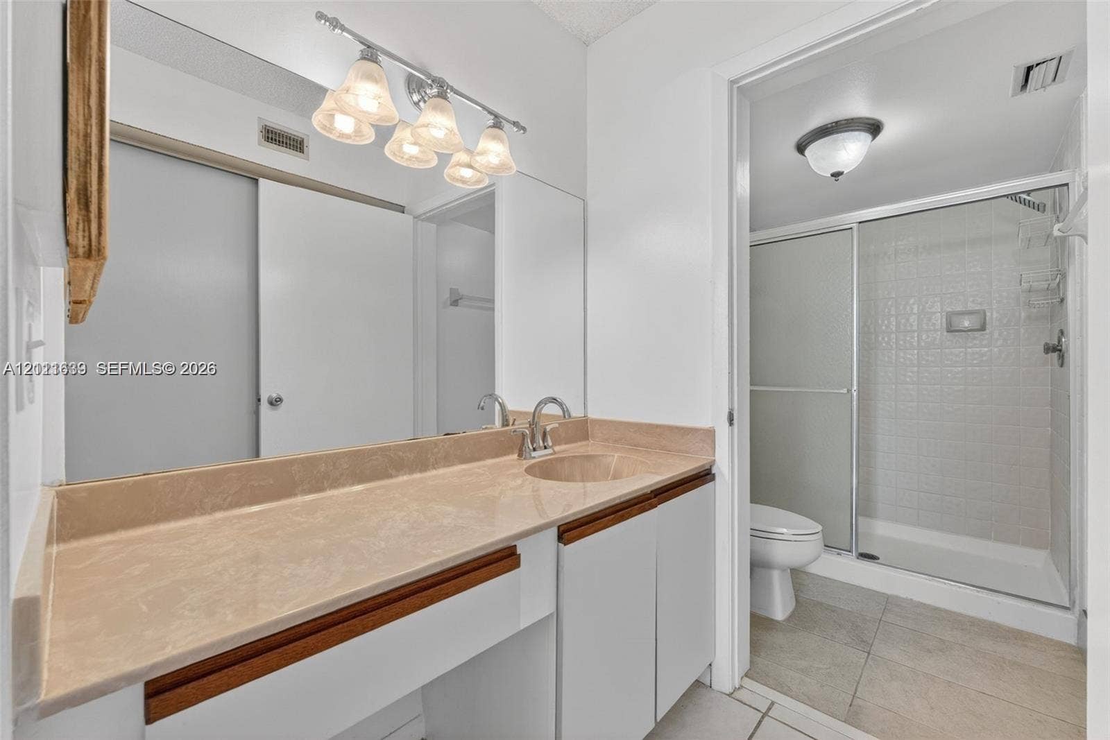 2768 S Carambola Circle S, #206, Coconut Creek, Coconut Creek, FL 33066 Bathroom featuring a wide vanity with a solid-surface countertop, an integrated sink, a full-width wall mirror, and a walk-in shower with a glass enclosure