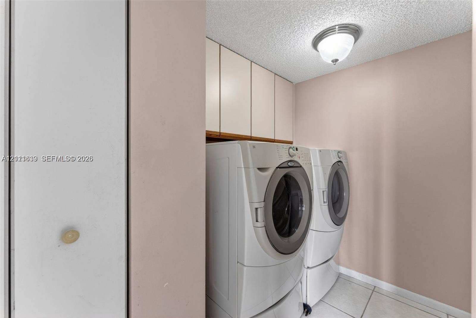 2768 S Carambola Circle S, #206, Coconut Creek, Coconut Creek, FL 33066 Laundry area featuring floor-to-ceiling built-in cabinetry, ceramic tile flooring, and a flush-mount ceiling light fixture