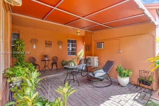 12801 SW 248th Terrace, Homestead, FL 33032 Covered patio featuring brick pavers, a metal frame overhead structure, and wall-mounted exterior lighting