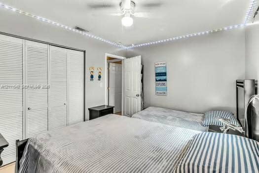 12801 SW 248th Terrace, Homestead, FL 33032 Bedroom featuring white louvered closet doors, a central ceiling fan with integrated lighting, and crown-molding recessed accent lighting