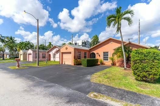 12801 SW 248th Terrace, Homestead, FL 33032 Single-story residence featuring a painted stucco exterior, attached one-car garage, asphalt driveway, arched entryway, and mature landscaping