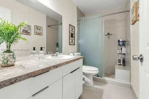 12801 SW 248th Terrace, Homestead, FL 33032 White cabinetry with flat-panel doors, stone-patterned countertop, integrated basin sink, and walk-in shower featuring a frosted glass sliding door