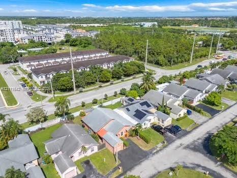12801 SW 248th Terrace, Homestead, FL 33032 Aerial perspective of a suburban neighborhood featuring single-story residences with pitched roofs, integrated solar panels, asphalt driveways, and manicured lawn areas
