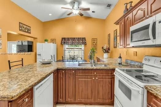 12801 SW 248th Terrace, Homestead, FL 33032 Kitchen featuring a vaulted ceiling, stained wood cabinetry, stone-finish countertops, stainless steel dual-basin sink, and recessed lighting