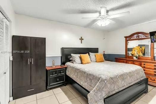 12801 SW 248th Terrace, Homestead, FL 33032 Bedroom featuring neutral-toned tile flooring, dual-door closet with louvered panels, and a central ceiling fan with integrated lighting