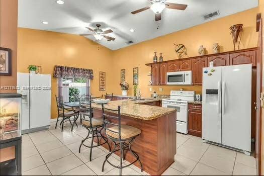 12801 SW 248th Terrace, Homestead, FL 33032 Kitchen featuring cathedral ceilings, custom wood cabinetry, an expansive island with a stone-composite countertop, tile flooring, and dual ceiling fans