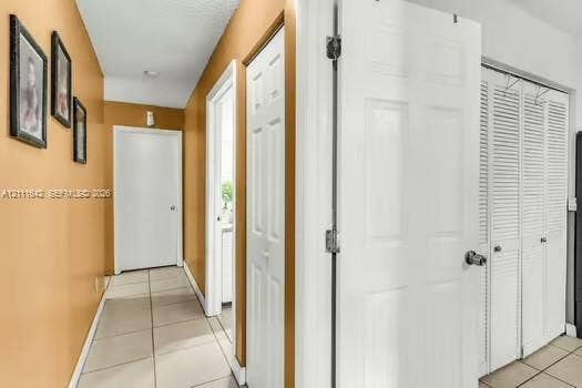 12801 SW 248th Terrace, Homestead, FL 33032 Interior hallway featuring neutral-toned ceramic tile flooring, solid-core interior doors, and white louvered-style closet doors