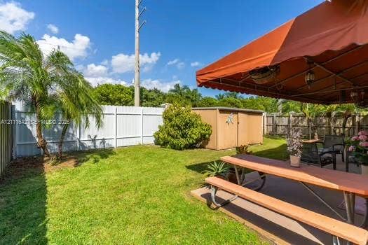 12801 SW 248th Terrace, Homestead, FL 33032 Fenced backyard featuring a manicured lawn, palm tree, concrete patio, and detached storage shed