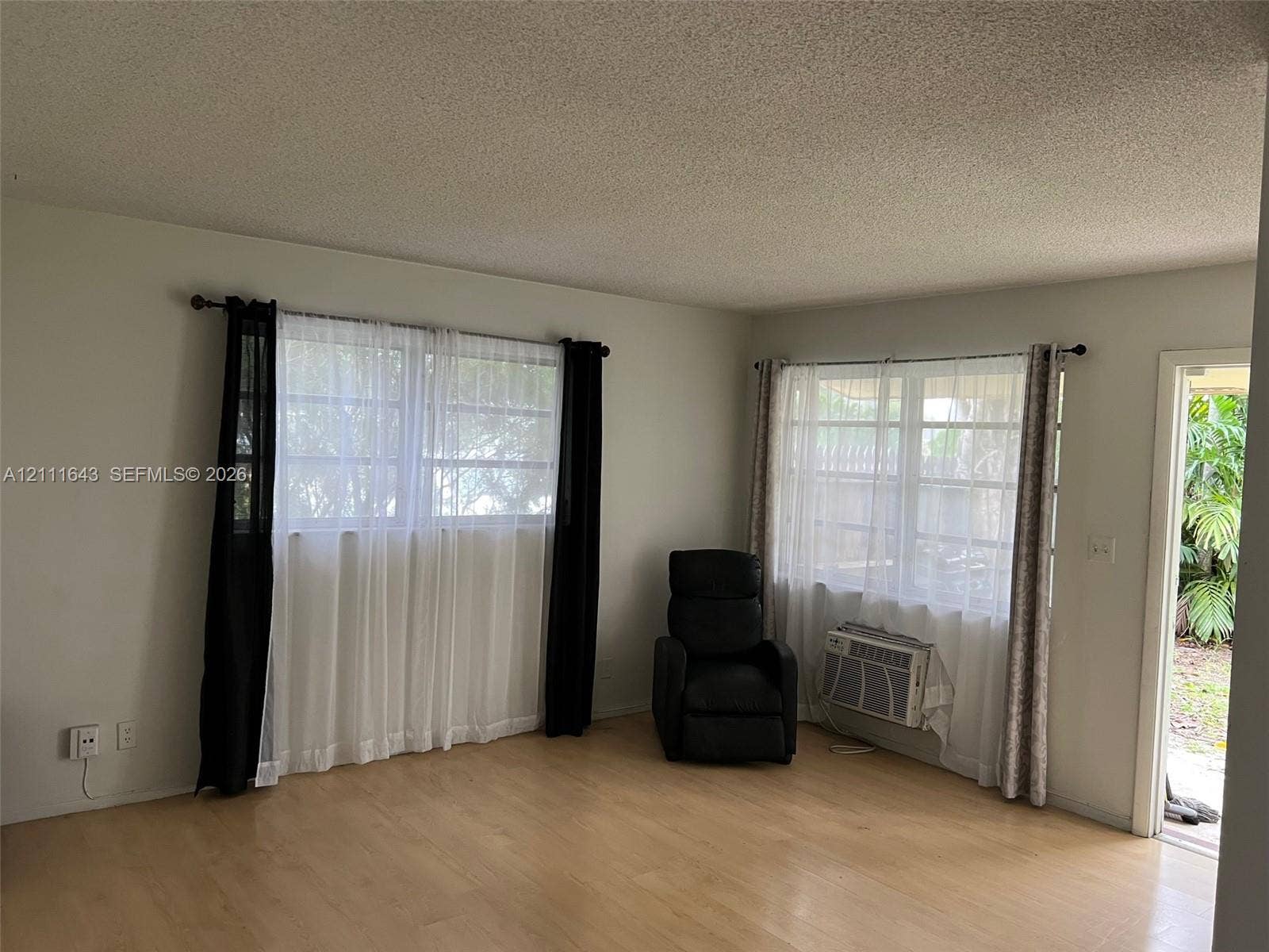 4841 SW 45th Avenue, #1, Hollywood, Hollywood, FL 33314 Interior area featuring wood-finish flooring, dual windows with grid detailing, and an integrated through-wall air conditioning unit