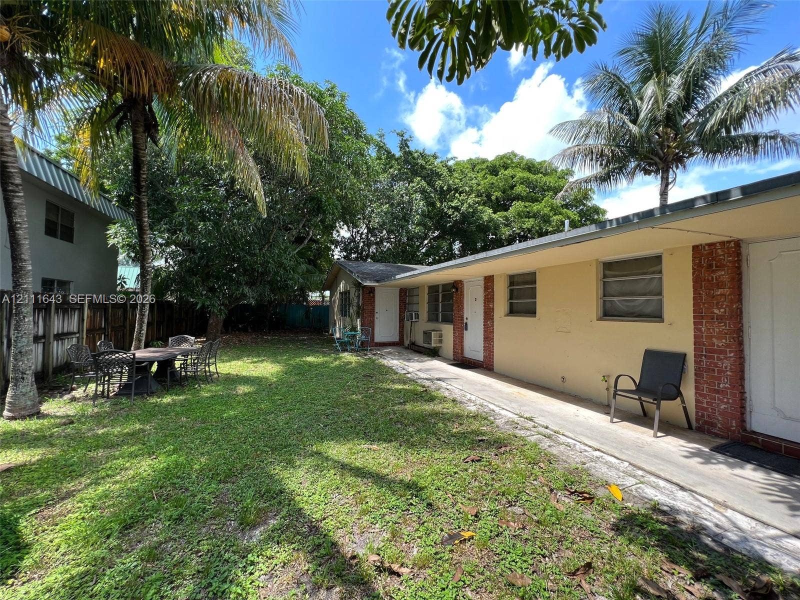 4841 SW 45th Avenue, #1, Hollywood, Hollywood, FL 33314 Rear exterior featuring a concrete walkway, brick masonry accents, mature palm trees, and a lawn area