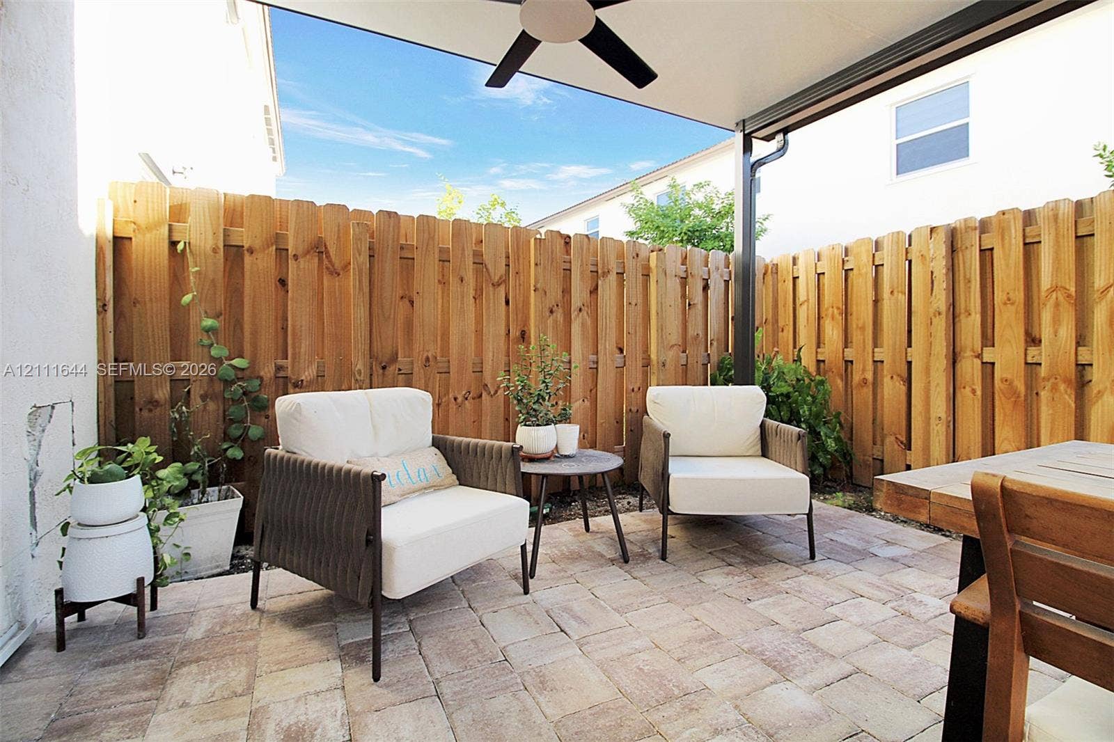 2873 SE 24th Avenue, Homestead, FL 33035 Covered outdoor patio featuring stone-paver flooring, a ceiling-mounted fan, and natural wood privacy fencing