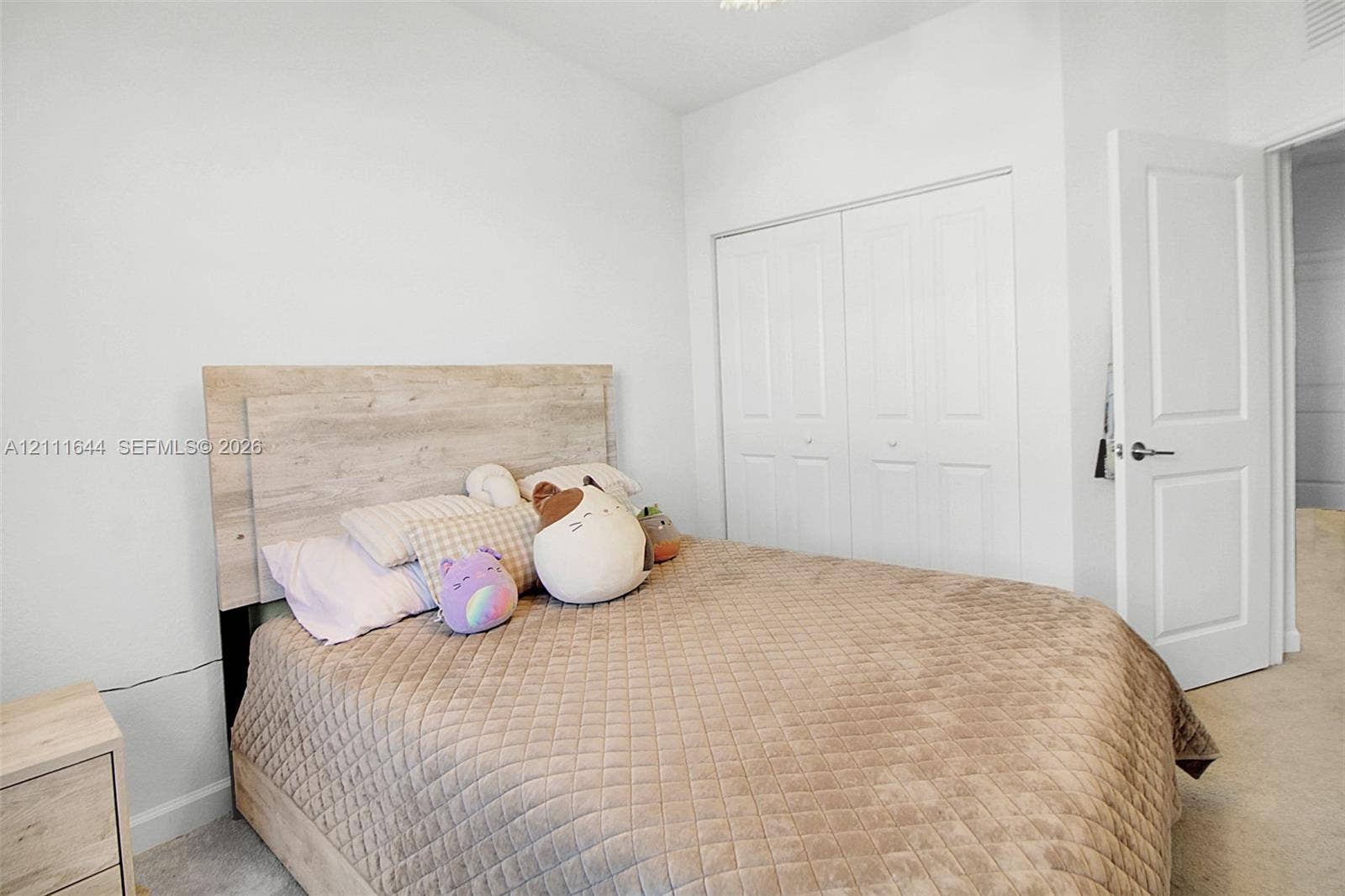 2873 SE 24th Avenue, Homestead, FL 33035 Neutral-toned room featuring light-colored wall-to-wall carpeting, high-reaching ceilings, and a built-in double-door closet with paneled detailing