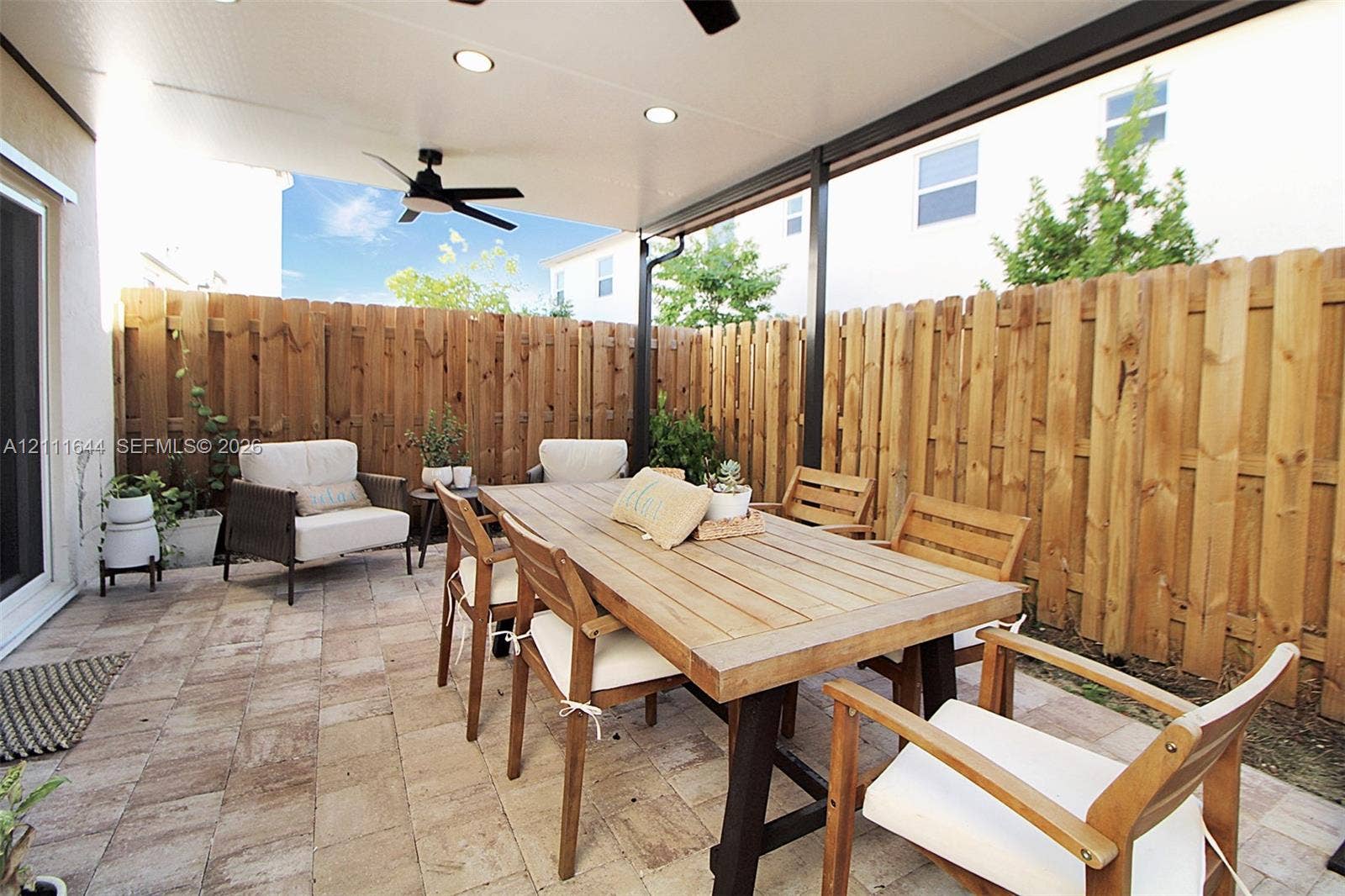 2873 SE 24th Avenue, Homestead, FL 33035 Covered patio featuring paver flooring, a wooden perimeter privacy fence, and a mounted ceiling fan with integrated lighting