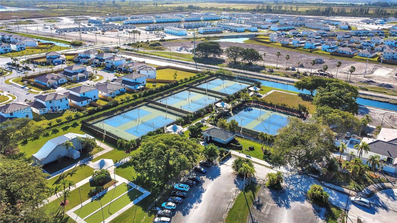 2873 SE 24th Avenue, Homestead, FL 33035 Aerial perspective of community recreational facilities featuring multiple tennis courts, pickleball courts, paved walking paths, and landscaped green spaces