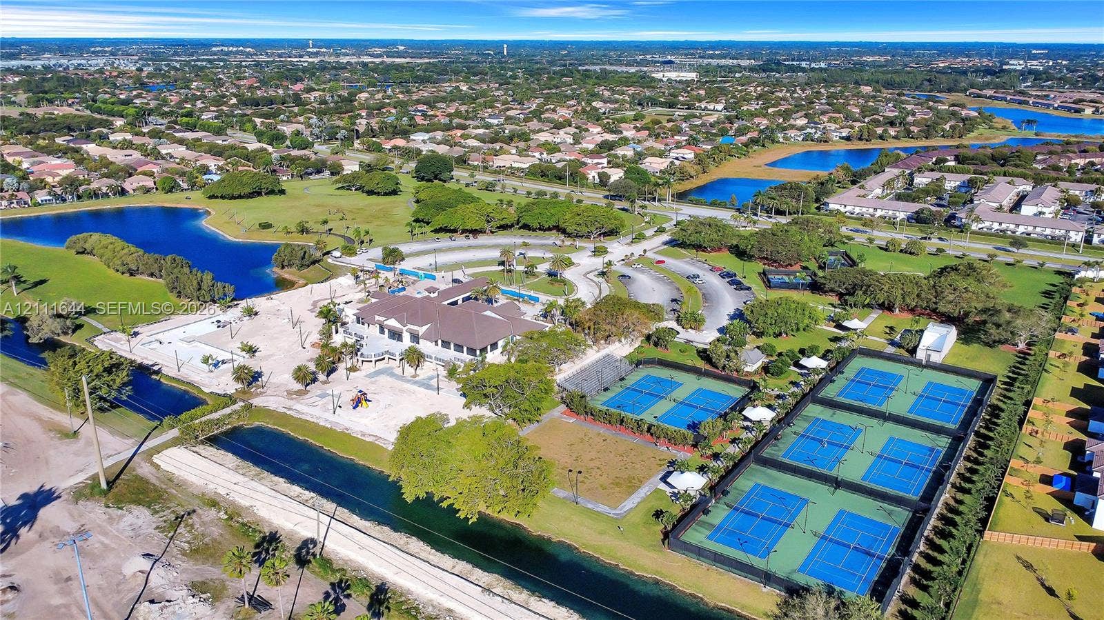 2873 SE 24th Avenue, Homestead, FL 33035 Aerial perspective of a multi-facility recreational complex featuring multiple tennis courts, a central clubhouse, and integrated water features
