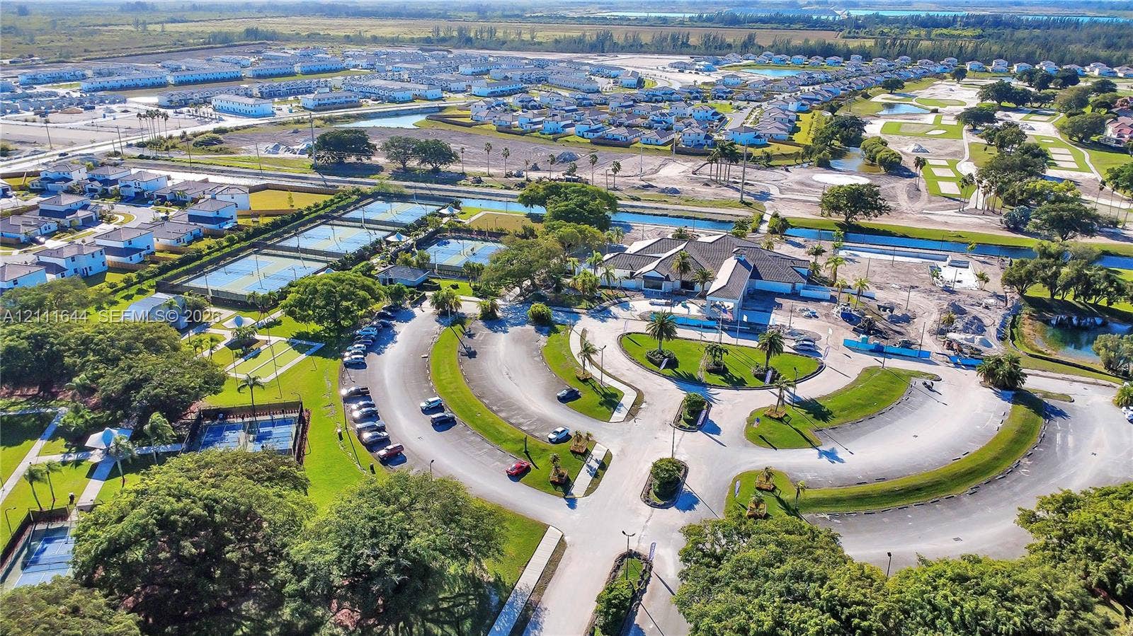 2873 SE 24th Avenue, Homestead, FL 33035 Aerial perspective of community recreational facilities featuring multiple tennis courts, a central clubhouse, an outdoor swimming pool, and landscaped green spaces with mature trees